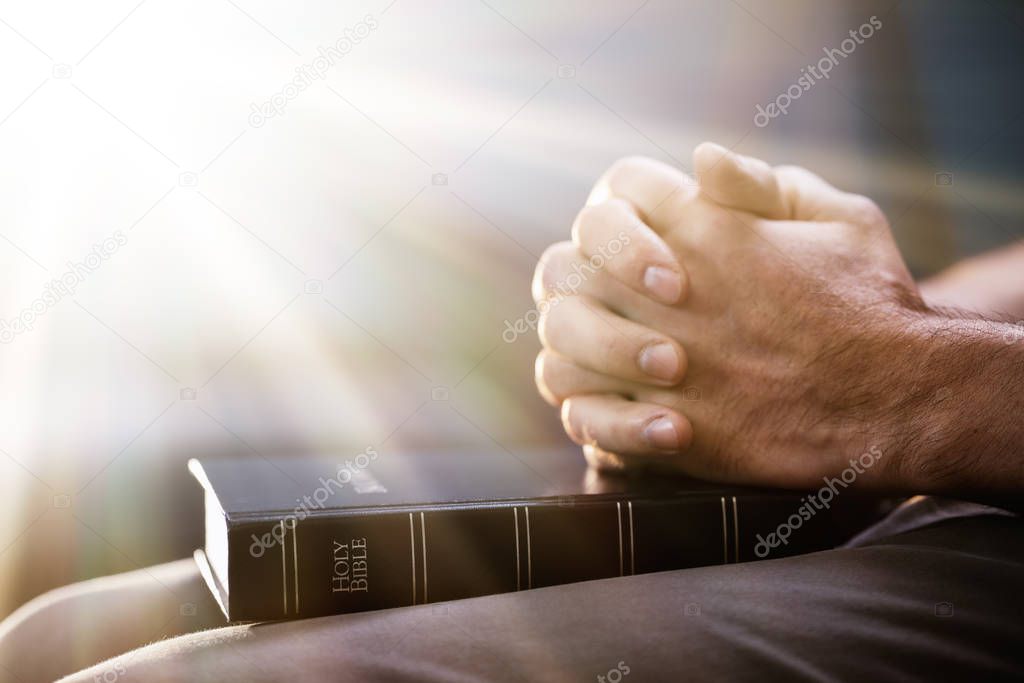 Sunlight Falling On Hand Over Bible While Praying