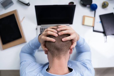 Dizüstü bilgisayarın önündeki stresli iş adamının yüksek açılı görüntüsü
