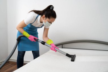 Elektrikli süpürge kullanan kadın temizleyiciden yatak temizleme servisi