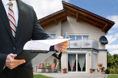 Bir Adamın Evrakları Kontrol Etmesinin Ortası Çatıda Güneş Panelleri Olan Evin Yakınında Duruyor
