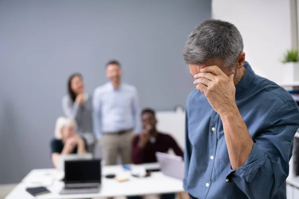 一个与同事一起嘲笑她的背景的悲伤商人的画像 — 图库照片