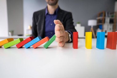 Domino 'nun beyaz masaya düşmesini engelleyen bir kadının yakın çekimi.