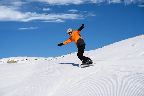 Happy Young Male Snow Boarder Enjoying Riding Snow Board On Track Against Snowcapped Mountains