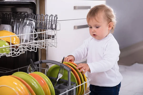 小さな女の子は自宅で台所で食器洗い機をアンロード — ストック写真