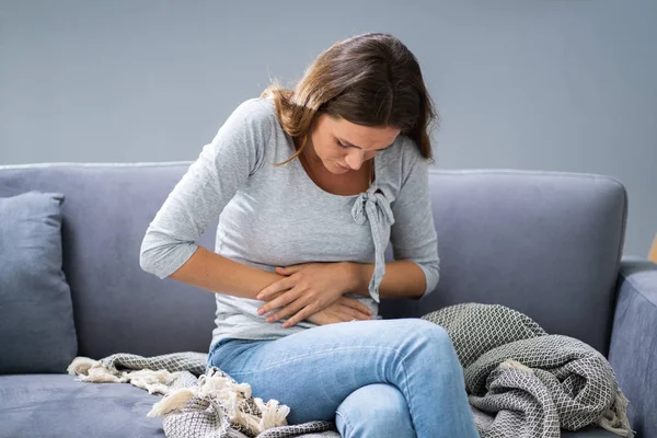 Porträt Einer Frau Mit Bauchschmerzen Auf Sofa Sitzend — Stockfoto