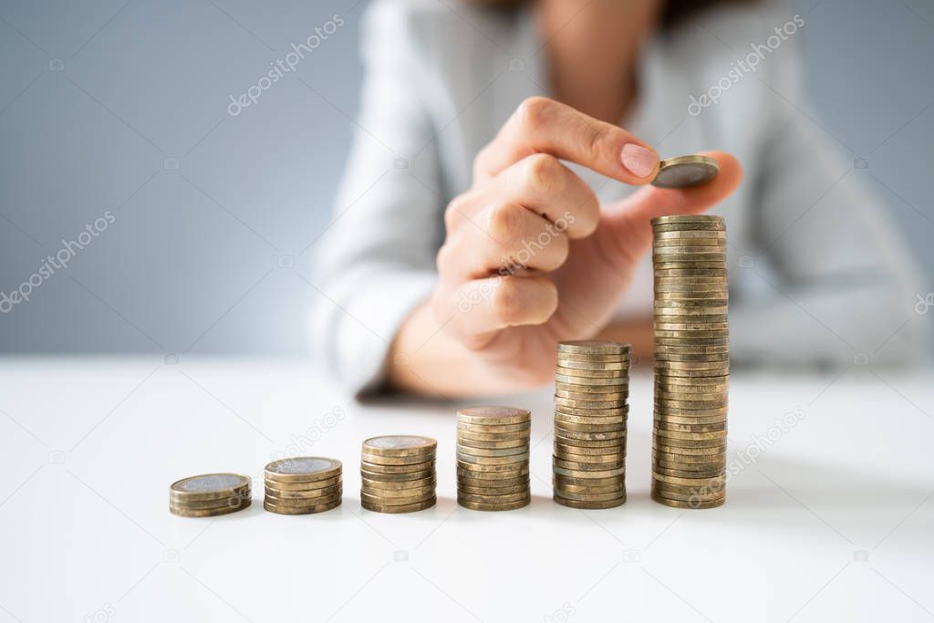 Close-up Of Businesswoman Hand Put Coins To Stack Of Coins