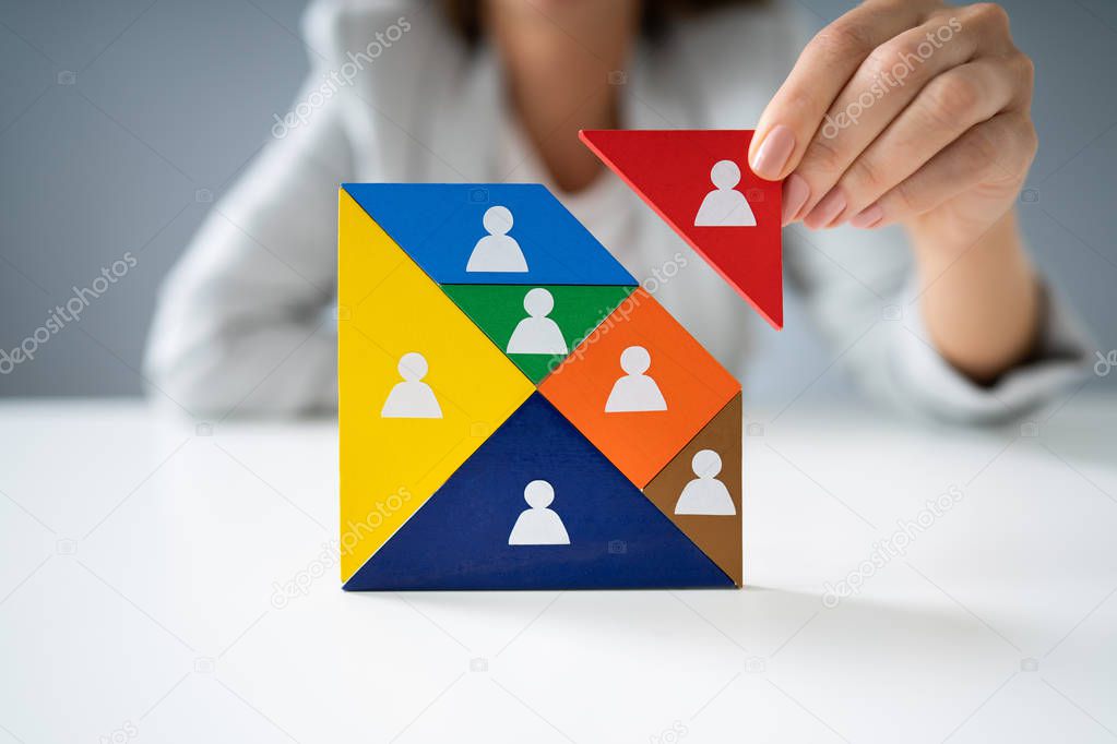 Businesswoman's Hand Building Tangram Square Block With Human Figures