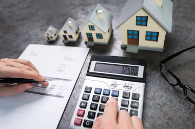 Küçük ve Büyük Ev Modelleri Vergilerini Hesaplayan İşadamı