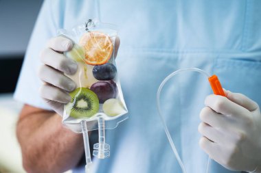 Erkek Doktor Saline Bag 'i hastanenin içinde meyve dilimleriyle tutuyor.