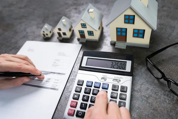 Biznesmen Obliczanie Podatku Przez Małe Duże Modele Domów — Zdjęcie stockowe