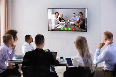 Gülümseyen İş Adamları Grubu, iş arkadaşlarıyla ofislerinde video konferansı yapıyorlar.