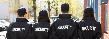 Security Guards With Hands Behind Back Standing In A Row Outside clipart