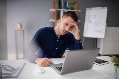 Ofiste dizüstü bilgisayarda çalışan stresli iş adamı.