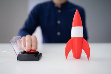 Businessman's Hand Launching Rocket By Pressing Red Button clipart
