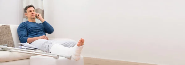 Jeune Homme Souriant Avec Jambe Cassée Assis Sur Canapé Parlant — Photo