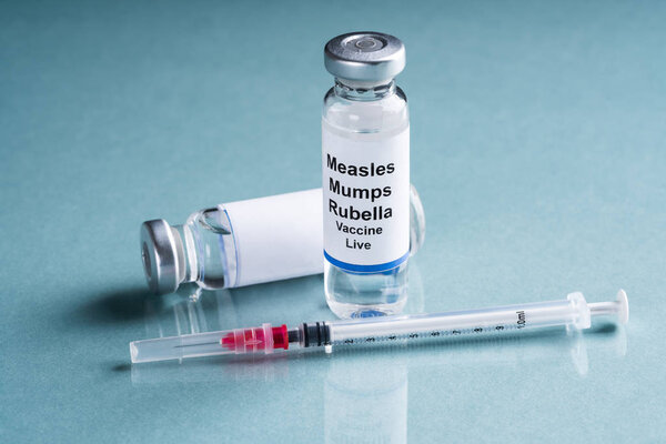 Measles Mumps Rubella Vaccine Vials With Syringe Over Turquoise Background
