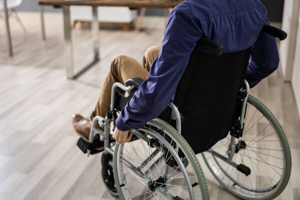 Крупный план бизнесмена, сидящего на инвалидной коляске в офисе
