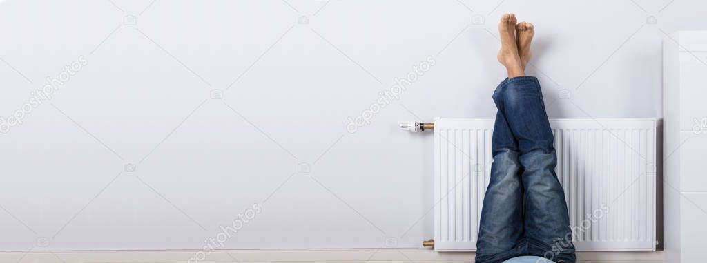 Man Warming Up His Feet On Radiator At Home