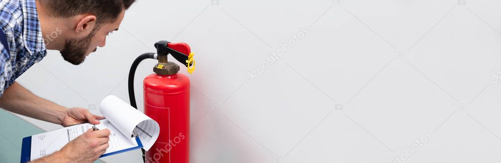 Close-up Of Technician Using Digital Tablet Checking Fire Extinguisher