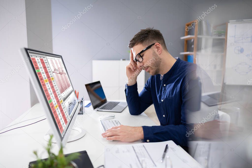 Portrait Of Young Businessman Using Computer At Desk
