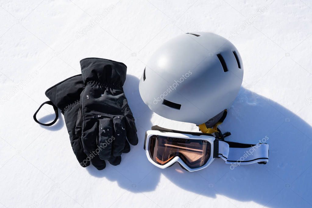 Gloves And Goggles In Snow Against Blurred Mountain Background