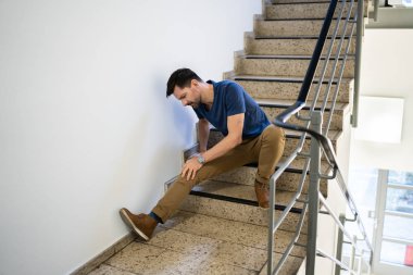 Kayma ve düşme sonrası merdivende oturan adam.
