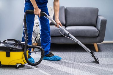 Photo Of Janitor Cleaning Carpet With Vacuum Cleaner clipart