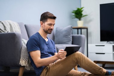 gülümseyen adam evde dijital tablet kullanma