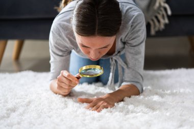 Young Female Looking At Carpet With Magnifying Glass clipart