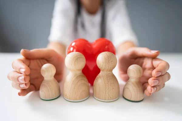 Arzthand Bedeckt Die Hölzerne Pfandfamilie Und Rotes Herz Auf Weißem — Stockfoto