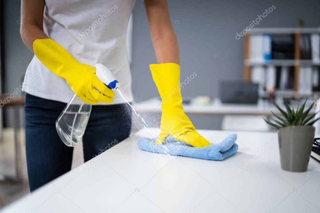 Young Worker Cleaning Desk With Rag In Office
