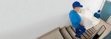 Sofa evin merdiven üzerinde taşıyan iki erkek Movers yüksek açılı görünüş