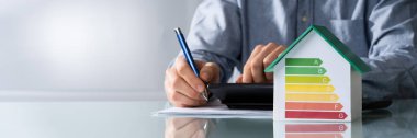Midsection işadamı ile enerji verimli grafik Office Ev modeli üzerinde fatura hesaplama