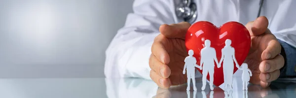 Close Mão Médico Protegendo Família Cortada Com Forma Coração Vermelho — Fotografia de Stock