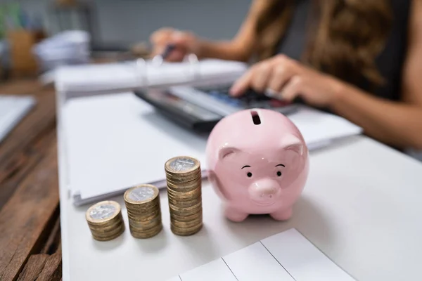 Affärskvinna Använda Räknemaskin Med Piggybank Och Stapel Mynt Skrivbordet — Stockfoto