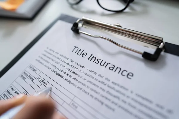 Woman Filling Title Insurance Form Over White Desk