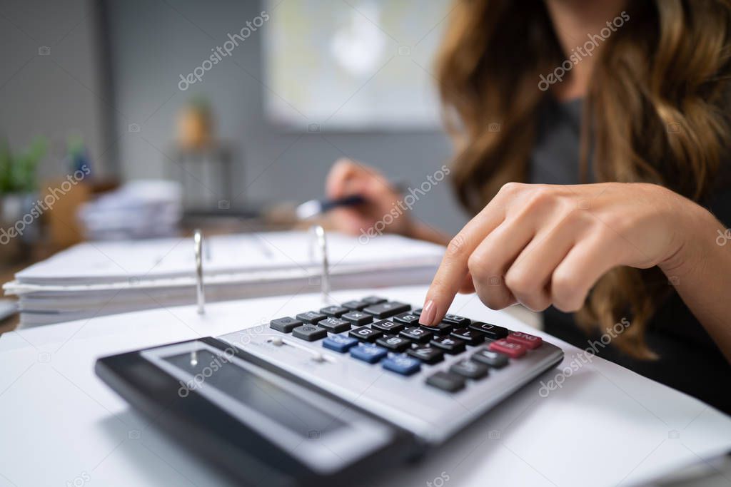 Close-up Of A Businessperson's Hand Calculating Bill With Calculator