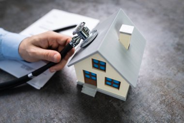 Ahşap masadaki ev modelinin el ele tutuşan steteskopunun yakın çekimi