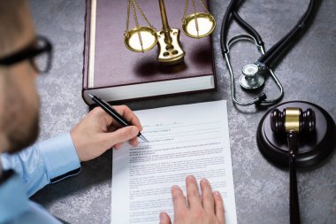 Yargıç çekiç ve steteskopla belgeye yazı yazıyor.