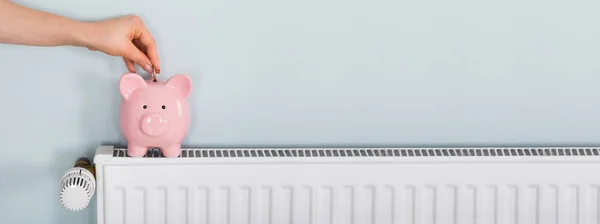 Man Hand Munt Invoegen Piggy Bank Radiator Besparen Energierekening — Stockfoto