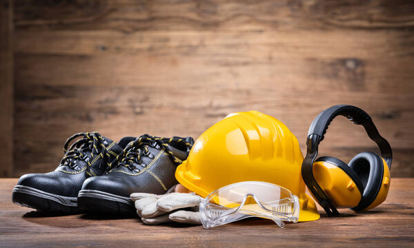 Close-up Of Ear Muff, Safety Glasses, And White Gloves On The Wooden Table