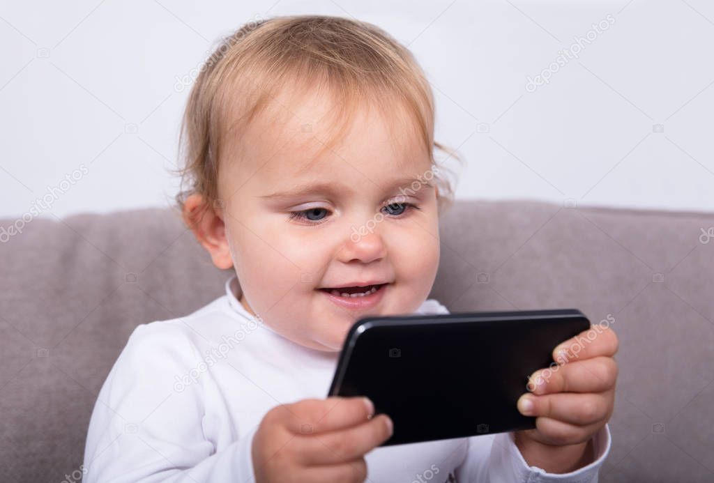 Little Girl With Mobile Phone At Home