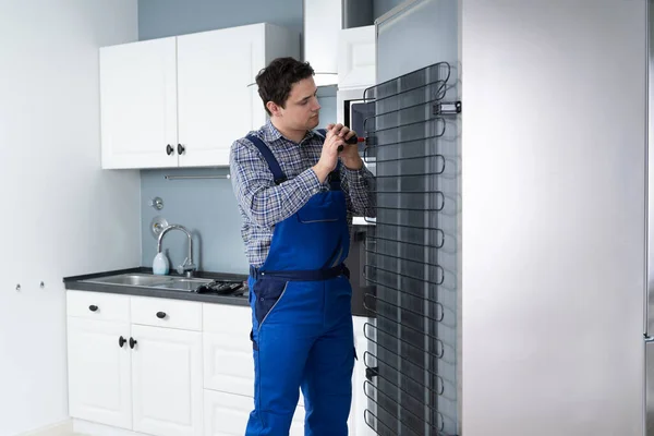 男工人修理冰箱用螺丝刀在房子 — 图库照片