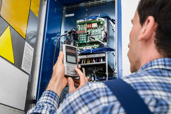 Foto Des Jungen Männlichen Technikers Der Fusebox Untersucht — Stockfoto