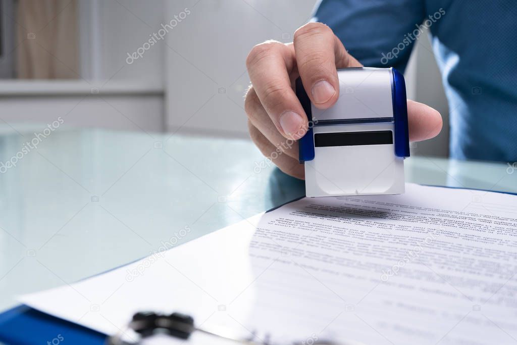 Close-up Of Businessman Hand Using Stamper On Document