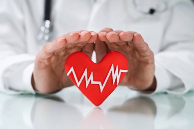 Doktor kalp ile beyaz kalp atışı darbe simgesi beyaz masa üzerinde koruma Close-up