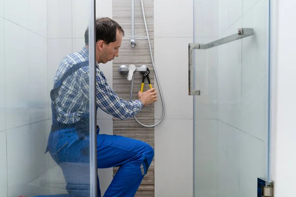 シャワーで若い男性配管工固定蛇口 — ストック写真