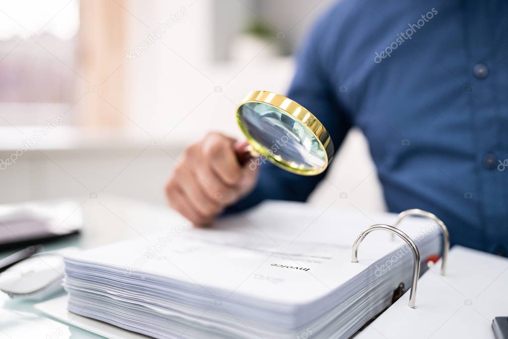 Businessman Looking At Document Through Magnifying Glass