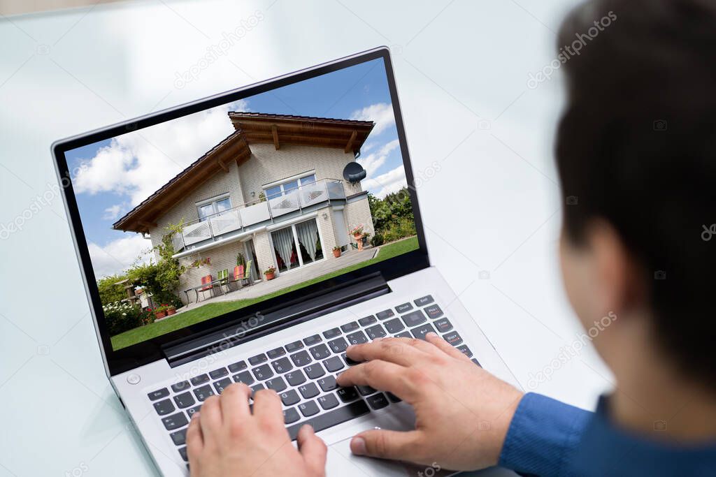 Man Selecting New House On Laptop At Home
