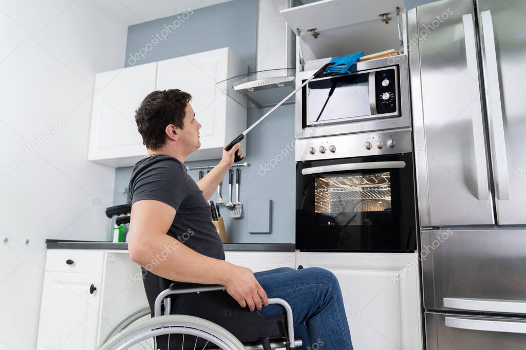 Disabled Man Using Grabber Tool To Grab Potholders In Kitchen